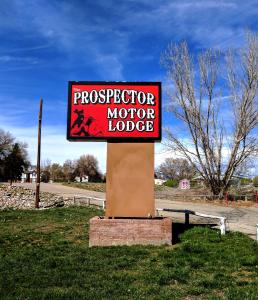 um sinal para um alojamento de turismo selvagem num poste na relva em Prospector Motor Lodge em Blanding