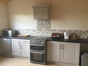 a kitchen with white cabinets and a stove top oven at Westport Glamping at Doon Angus Farm in Westport