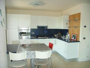 una cocina con una mesa con armarios blancos y sillas blancas en Appartamento Adelaide, en Grado