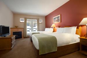 a hotel room with a large bed and a television at Sundance Lodge in Sun Peaks