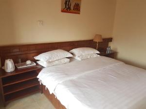 a bedroom with a bed with white sheets and pillows at China Garden in Nairobi