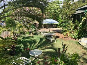 a garden with a table and chairs and an umbrella at Hakuna Matata Maui Hostel in Lahaina
