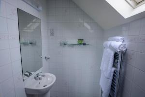 a white bathroom with a sink and a mirror at The Pipers Rest in Doolin