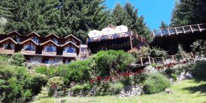 a group of buildings on a hill with flowers at Dos Bahias Lake Resort in Villa La Angostura