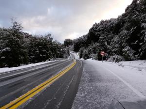 an empty road covered in snow with a stop sign at Dos Bahias Lake Resort in Villa La Angostura