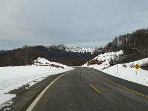an empty road with snow on the sides of it at Dos Bahias Lake Resort in Villa La Angostura