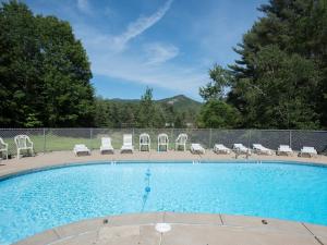 a large swimming pool with chairs and a fence at Colonial Motel in North Conway