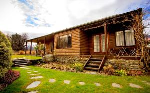 a wooden house with a lawn in front of it at Glenorchy Lake House in Glenorchy