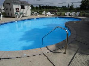 une grande piscine avec de l'eau bleue et des chaises dans l'établissement Amish Country Motel, à Bird-in-Hand