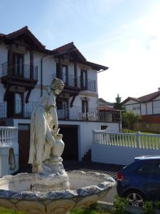 a statue of a woman in a fountain in front of a house at Apartamentos La Fuente de Enmedio in Suances