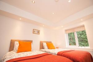 2 łóżka z pomarańczowymi poduszkami w sypialni w obiekcie Warren House w mieście Doncaster