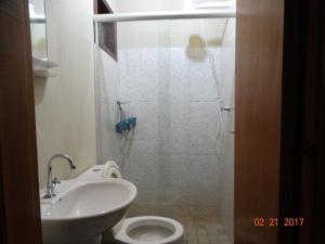 a bathroom with a shower and a toilet and a sink at Chalés Bangalôs Itamambuca in Ubatuba