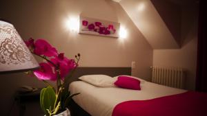 - une chambre avec un lit et un vase avec des fleurs roses dans l'établissement Hôtel des Barrages, à Brommat