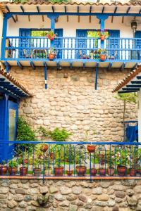 a stone building with blue balconies and potted plants at Rumi Wasi in Cusco
