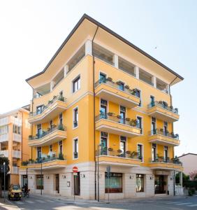 ein gelbes Gebäude mit Balkonen auf einer Straße in der Unterkunft Hotel Villa Venezia in Grado