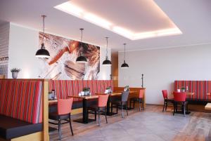 a restaurant with tables and chairs and a painting on the wall at Aparthotel Paderborn in Paderborn