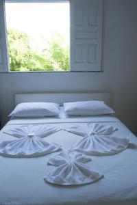 1 cama blanca con 2 almohadas blancas y una ventana en Pousada Valmar, en Aracaju