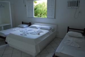 2 camas en una habitación blanca con ventana en Pousada Valmar, en Aracaju
