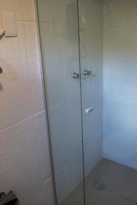 um chuveiro com porta de vidro em um banheiro em Chalés entre Nuvens e Estrelas em Monte Verde