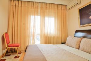 een slaapkamer met een bed, een rode stoel en een raam bij Gold Hotel in Korçë
