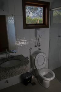 uma casa de banho com um WC, uma banheira e uma janela. em Chalés entre Nuvens e Estrelas em Monte Verde