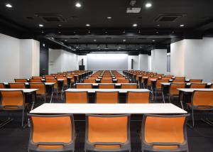 an empty lecture hall with tables and chairs at HOTEL MYSTAYS Ochanomizu Conference Center in Tokyo