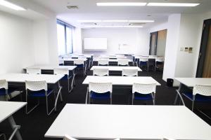 an empty classroom with white tables and chairs at HOTEL MYSTAYS Ochanomizu Conference Center in Tokyo