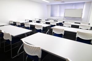 an empty classroom with tables and chairs and a whiteboard at HOTEL MYSTAYS Ochanomizu Conference Center in Tokyo