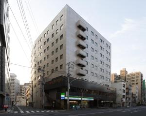 a tall white building on a city street at HOTEL MYSTAYS Ochanomizu Conference Center in Tokyo