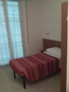 a bedroom with a bed with a red blanket and a window at Hotel Trinidad in Rimini
