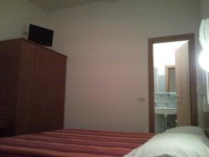 een slaapkamer met een bed, een dressoir en een raam bij Hotel Trinidad in Rimini