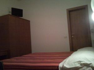 a bedroom with a bed and a dresser with a television on it at Hotel Trinidad in Rimini