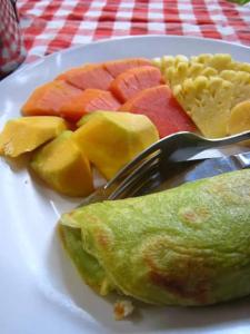a plate of food with fruit on a plate with a fork at Indraprastha Ubud Home Stay in Ubud
