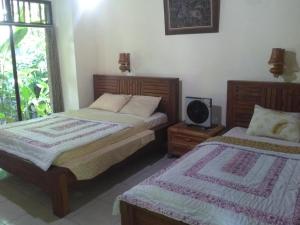 a bedroom with two beds and a tv in it at Indraprastha Ubud Home Stay in Ubud