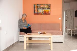 a woman sitting on a couch reading a book at Efrilias Studios & Apartments in Kissamos