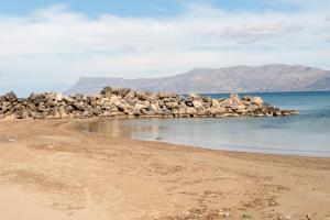 a beach with a pile of rocks in the water at Efrilias Studios & Apartments in Kissamos