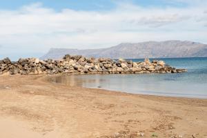 a beach with a pile of rocks in the water w obiekcie Efrilias Studios & Apartments w mieście Kisamos