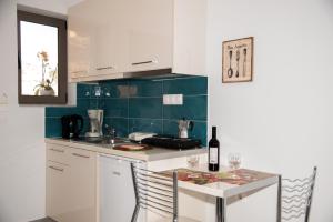 a kitchen with white cabinets and a table with a bottle of wine at Efrilias Studios & Apartments in Kissamos