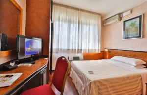 una camera d'albergo con letto e scrivania con TV di David Palace Hotel a Porto San Giorgio