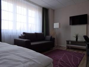 a living room with a couch and a tv at Garni Hotel Lavendelhof in Nauen