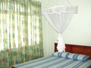a bedroom with a bed with a curtain at Tamarind Breeze in Bentota