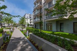 a walkway in front of a building with benches at Aquamarina Świnoujście Marina Invest in Świnoujście