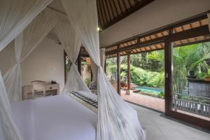 a bedroom with a white bed with mosquito nets at Virmas Private Villa in Ubud
