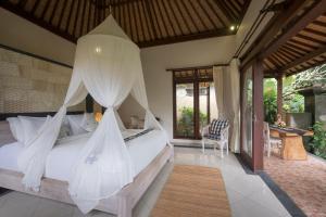 a bedroom with a bed with mosquito net at Virmas Private Villa in Ubud