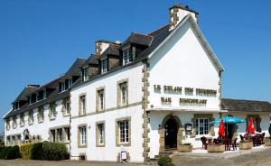 een groot wit gebouw met tafels ervoor bij Le Relais des Primeurs LOGIS HOTEL in Taulé