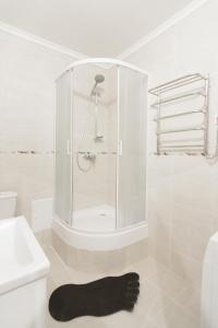 a white bathroom with a shower and a black rug at Club Suite near Deribasovskaya in Odesa