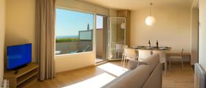 sala de estar con TV y mesa con sillas en Apartamentos Voramar, en Castelldefels