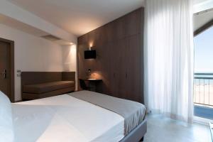 a bedroom with a bed and a chair and a window at Hotel Eden in Alba Adriatica