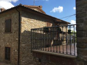 um edifício de pedra com uma cerca numa varanda em Appartamenti e Camere Il Poggio di D'Angeli Lidia em Auditore