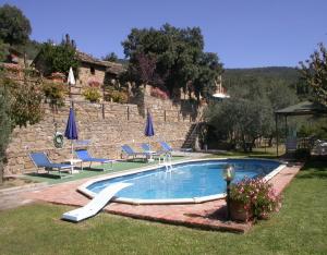 una piscina en un patio con sillas y sombrillas en Lauro, en Cortona